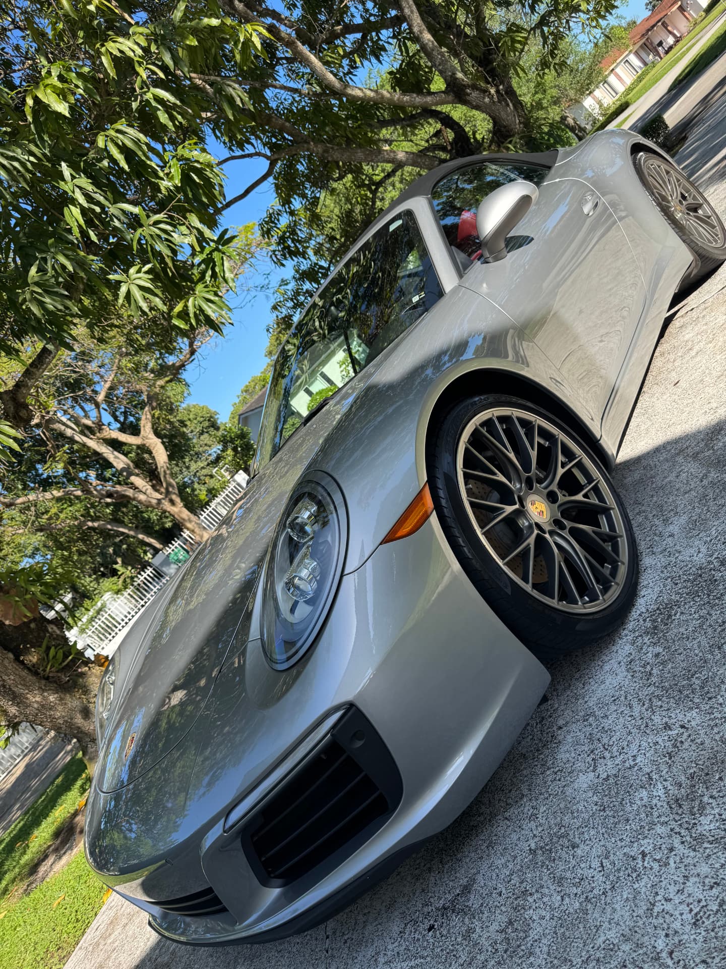 Silver convertible glossed to a mirror in a shaded driveway